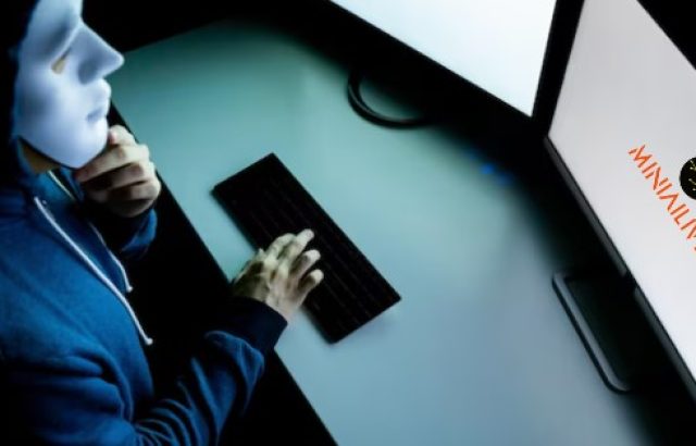 man with mask sitting in front of computer screen preventing online fraud